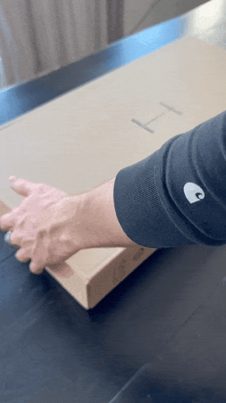 Close-up of hands opening a box with H-Tree branding, revealing neatly arranged, minimal packaging inside